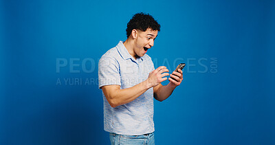 Buy stock photo Phone, surprise and man in studio with news, notification or lottery win on blue background. Wow, shock and happy person with mobile for discount deal, promotion or giveaway prize with mockup space