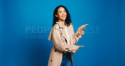 Buy stock photo Portrait, pointing and woman in studio with promotion, announcement and offer on blue background. Model, space and happy person with hand gesture, smile and opportunity with decision or choice