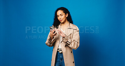 Buy stock photo Phone, reading and typing with woman in studio for connection, text message and social media. Online news feed, search and mockup space with person on blue background for post update and network