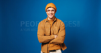 Buy stock photo Confidence, portrait and man in studio for fashion, smile and happiness on mockup space. Arms crossed, style and male model with trendy clothes, glasses and gen z outfit on blue background in Spain
