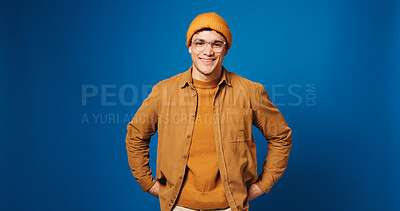 Buy stock photo Man, fashion and smile in studio portrait with beanie, glasses and trendy style on blue background. Person, happy and pride with confidence, edgy clothes and hat with mock up space in Costa Rica