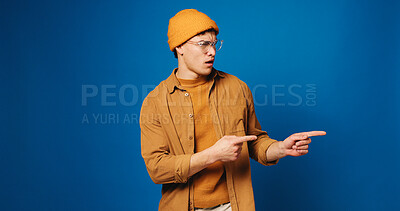 Buy stock photo Confused, man and pointing with smile in studio for advertising, announcement and coming soon. Unsure, male person and hand gesture for sign up, promotion offer and giveaway guide on blue background