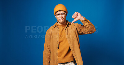 Buy stock photo Portrait, mockup and man in studio with thumbs down, choice and decision for university rating. Disagree, fail and college student with vote, dislike hand sign and opinion on blue background space.