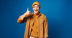 Happy man, portrait and fashion with thumbs up in studio for good choice on a blue background. Male person, model or gen z with smile, like emoji or yes sign for style, clothing or outfit on space