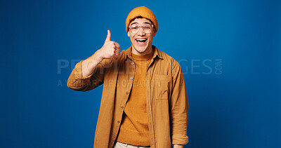 Buy stock photo Happy man, portrait and fashion with thumbs up in studio for good choice on a blue background. Male person, model or gen z with smile, like emoji or yes sign for style or clothing on mockup space