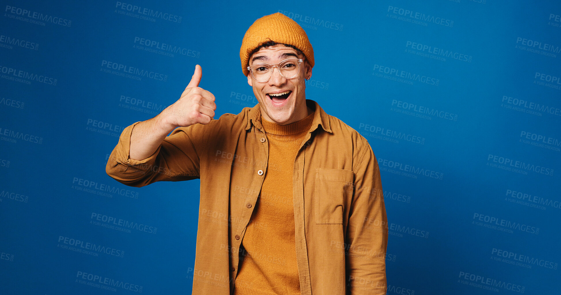 Buy stock photo Happy man, portrait and fashion with thumbs up for good review on a blue studio background. Excited, male person or model with like emoji, yes sign or OK for feedback, vote or success on mockup space
