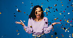 Happy woman, portrait and celebration with confetti in studio for winning on a blue background. Excited, female person or model with smile, bonus or surprise for good news, prize or lottery success