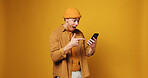 Phone, excited and man in studio with networking, communication or texting on mobile app. Mockup space, pointing and person with cellphone for chatting, contact or social media by yellow background.