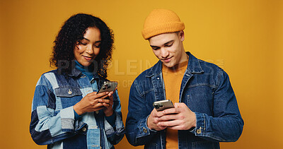 Buy stock photo Phone, happy and couple in studio with networking, communication or chatting on mobile app. Smile, technology and man with woman on cellphone for contact on social media together by yellow background