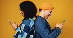 Phone, happy and couple in studio with networking, communication or social media on mobile app. Smile, technology and man with woman on cellphone for contact, chatting or texting by yellow background