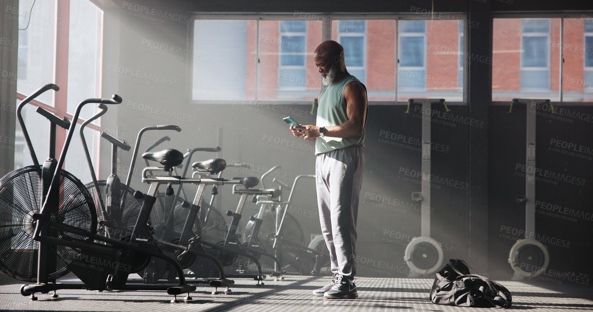 Buy stock photo Smartphone, fitness and black man in gym, internet and digital app to track progress. Mature person, cellphone or health center with equipment, connection or training facility with message to contact