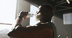 Fitness, exercise and man with drinking water at gym for hydration, workout recovery and resting. Athlete, window or mature person with liquid at sports club for training break, thirsty and nutrition