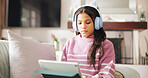 Tablet, headphones and child on sofa online for elearning, educational games and internet. Relax, weekend and girl on digital tech for watching videos, streaming movies and subscription in home