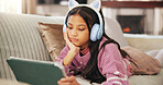 Tablet, headphones and child on sofa for watching videos, educational games and internet. Relax, weekend and girl on digital tech for elearning, streaming movies and online subscription in home