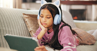 Buy stock photo Tablet, headphones and child on sofa for watching videos, educational games and internet. Relax, weekend and girl on digital tech for elearning, streaming movies and online subscription in home