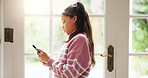 Girl, child and typing with phone in home for social media browsing, online game and web addiction. Kid, smartphone and texting by door with streaming subscription, internet dependence and scrolling