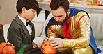 Halloween, help and father with boy, decoration and creativity with fun, drawing and holiday. Bonding together, home and dad with kid, learning and celebration with family party and pumpkin art