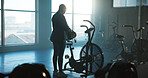 Back, exercise bike and woman in gym for start of cardio training, fitness or workout routine. Getting ready, machine and stationary bicycle with person in health club for cycling or spinning class