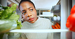Woman, thinking and hungry at fridge in home, choice and options with vegetables for meal. African person, decision and check shelf with healthy diet, ingredients and pov in kitchen at apartment