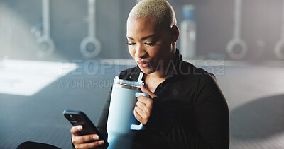 Buy stock photo Fitness, texting and woman with smartphone, gym and drinking water on break, wellness and hydration. Calm, athlete and African person with mobile for communication, relax and beverage in health club