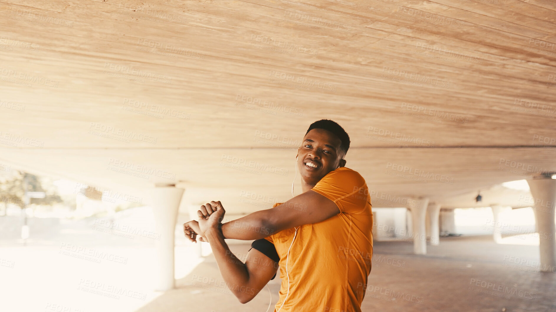 Buy stock photo Black man, portrait and stretching arms for fitness, warm up and earphones for cardio preparation. African person, smile and athlete for sports podcast, workout and getting ready for exercise outdoor