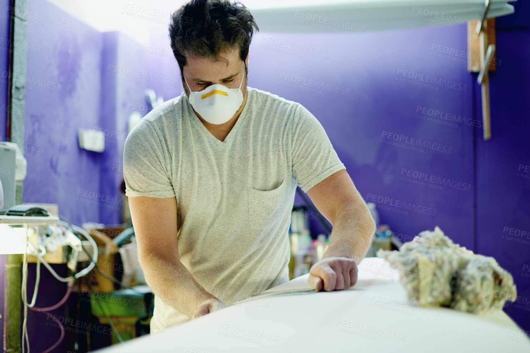 Buy stock photo Surfboard, craft and man with sandpaper in workshop for manufacturing, custom design and shape material. Entrepreneur, handmade production and person with foam plank, safety mask or sanding in studio