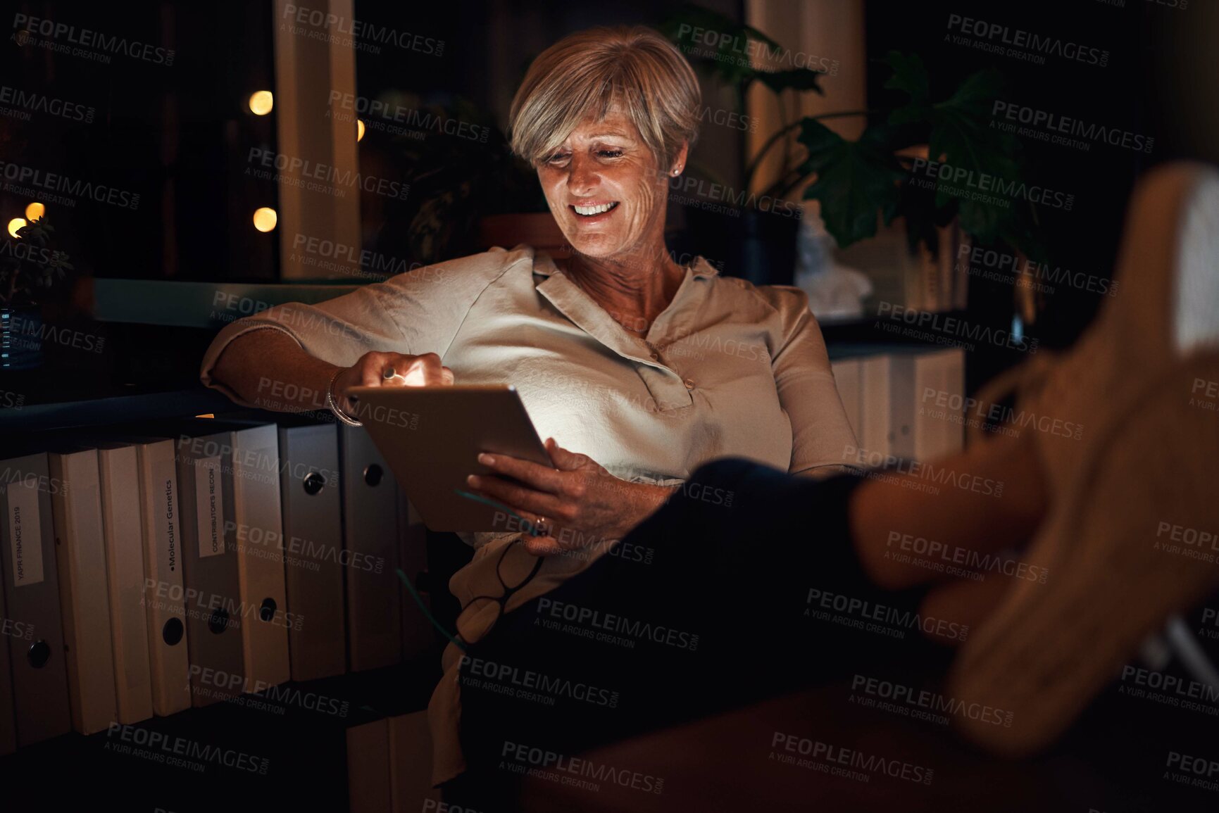 Buy stock photo Business, tablet and mature woman in home office with relax for notification, reading proposal or review. Night, online and happy person with technology for information, email or news article at desk