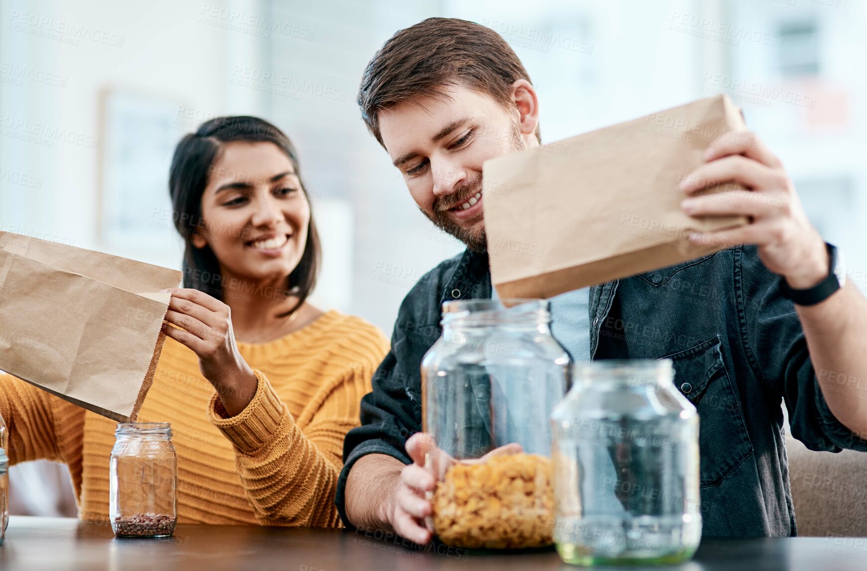 Buy stock photo Cereal, jar and pouring with interracial couple in kitchen of home together to organize food or groceries. Glass, paper bag or sorting with man and woman in apartment for diet, health or wellness