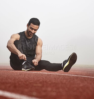 Buy stock photo Shot of a young male athlete tying his shoe laces before a race