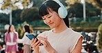 Headphones, phone and student with Japanese woman in park for streaming, University campus and online playlist. Music, radio and education podcast with person and mobile in Japan outdoor for college
