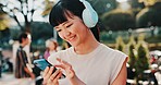 Music, phone and student with Japanese woman in park for streaming, University campus and online playlist. Headphones, radio and education podcast with person and mobile in Japan outdoor for college