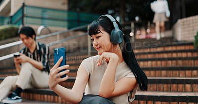 Buy stock photo Woman, selfie and headphones on stairs in city with streaming, memory and post on mobile app. Girl, person and influencer with live stream, profile picture or photography with music on steps in Japan