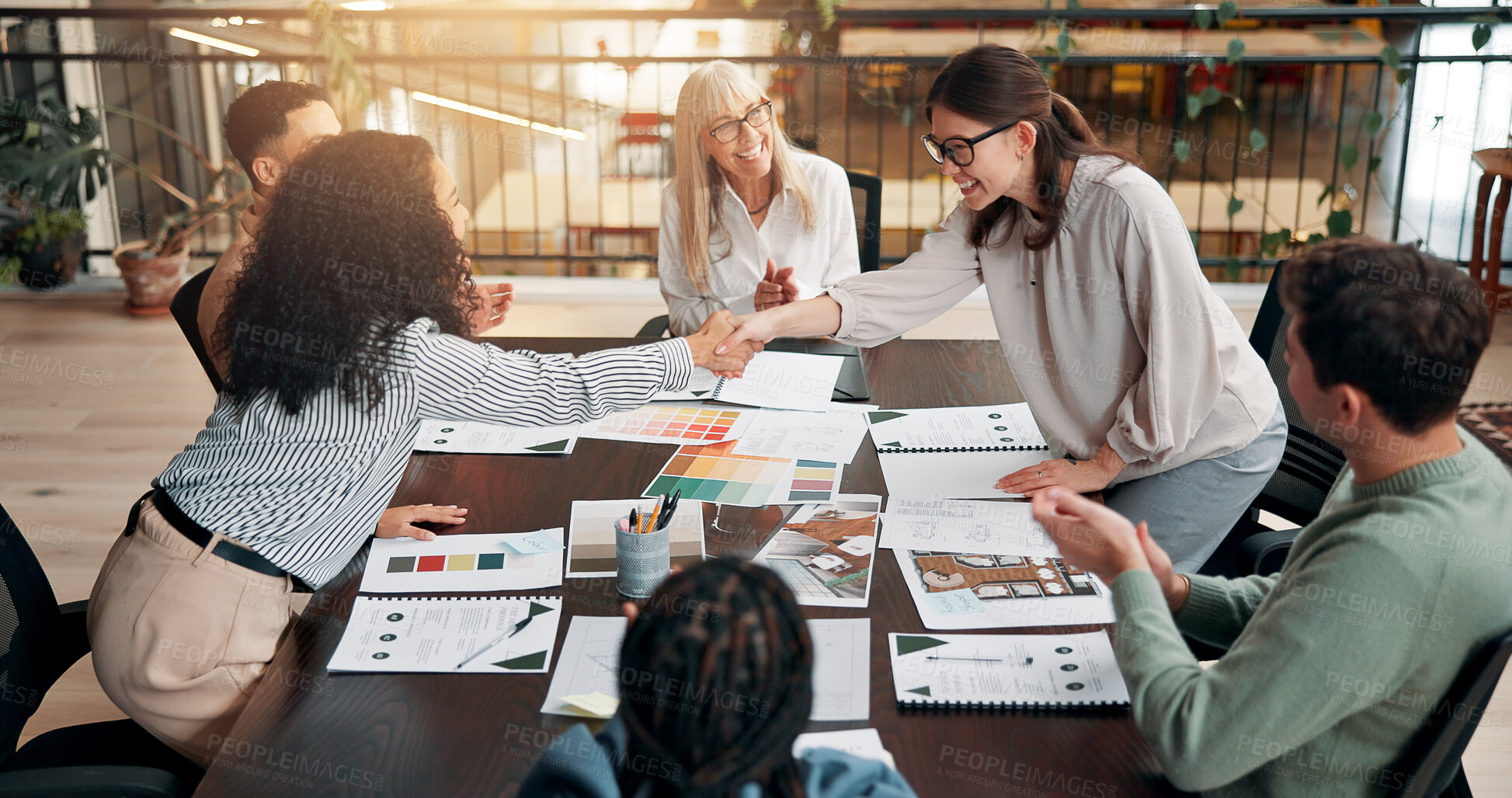 Buy stock photo Business people, meeting and handshake for team with applause, praise or congratulations at creative agency. Market research, paperwork and female employees shaking hands for well done or success
