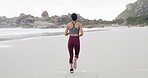 Back of woman, workout and run on beach for exercise, fitness or outdoor wellness. Female person, athlete or runner with marathon, preparation and cardio training with space in nature for health