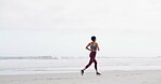 Woman, running and back at beach, fitness and training with space, sky and outdoor with routine. Person, workout and exercise for wellness, cardio challenge and jog by ocean for health in New Zealand