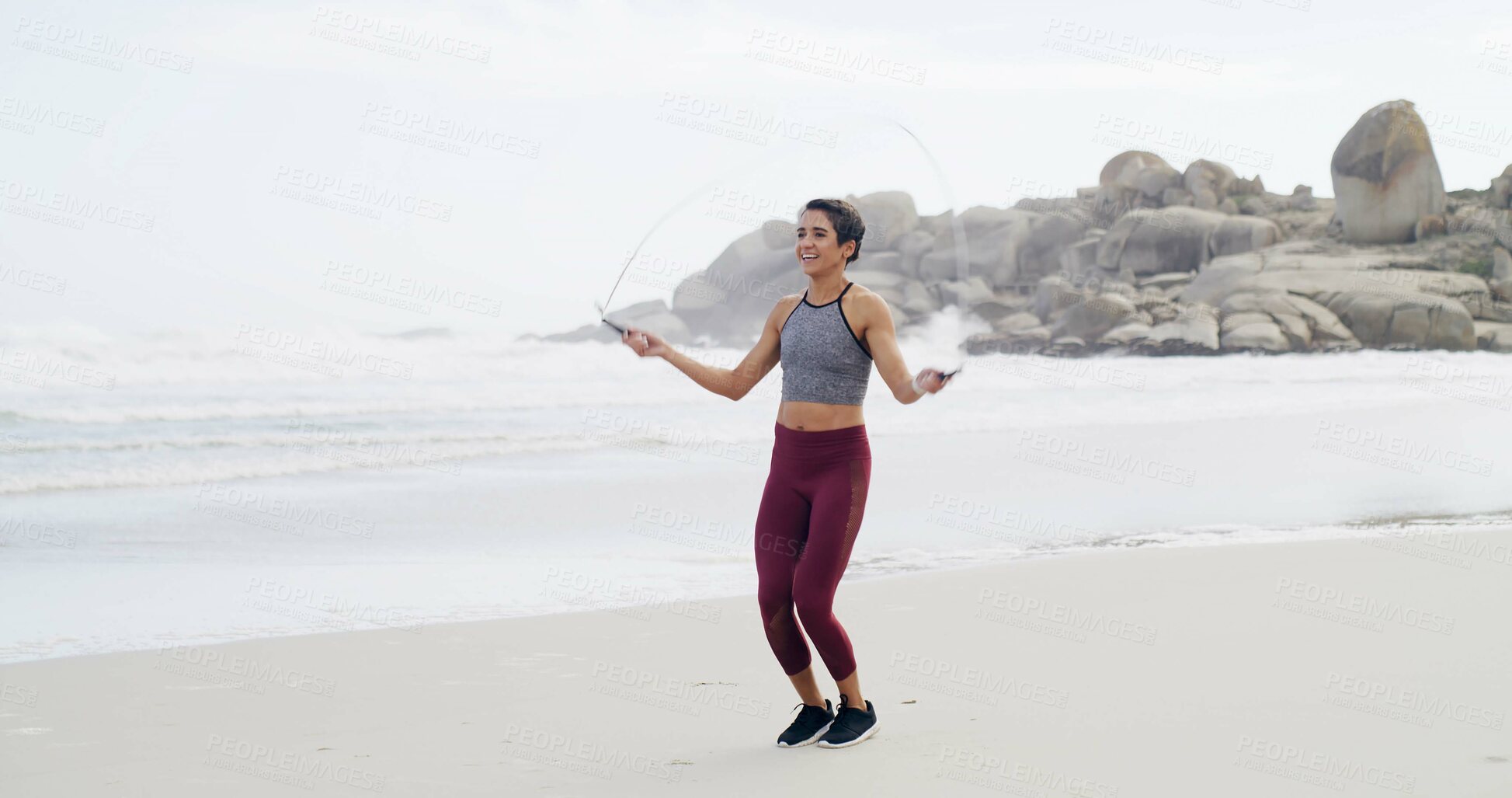 Buy stock photo Fitness, skipping and smile with woman on beach for cardio training or workout in morning. Exercise, jump rope and view of horizon with happy athlete person at ocean or sea for health challenge