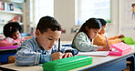 Education, students and boy writing in classroom for learning, fine motor skills or exam quiz. Development, children or books at school for study assessment, literacy knowledge or language evaluation