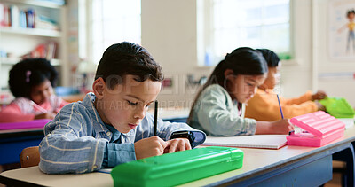 Buy stock photo Education, students and boy writing in classroom for learning, fine motor skills or exam quiz. Development, children or books at school for study assessment, literacy knowledge or language evaluation