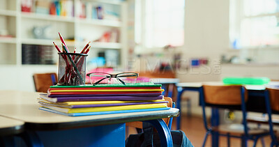 Buy stock photo Books, colors and glasses on desk in classroom for learning, education or knowledge with teaching. Spectacles, pencils and lesson at elementary school for assessment, test or project at academy.