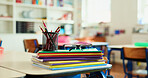 Books, colors and spectacles on desk in classroom for learning, education or knowledge with teaching. Glasses, pencils and lesson at elementary school for assessment, test or project at academy.