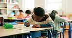 Education, students and boy writing in classroom for learning, fine motor skills or coordination. Development, child and test paper at school for assessment, literacy knowledge or academic assignment