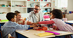 Hands together, education and teacher with kids in classroom for learning, support or assessment group. Celebration, child development and success with students and man in school for scholarship news