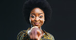 Portrait, black woman and pointing at you in studio for choice, selection or winner. Smile, decision and African person with finger gesture for vote, support or encourage on dark background space