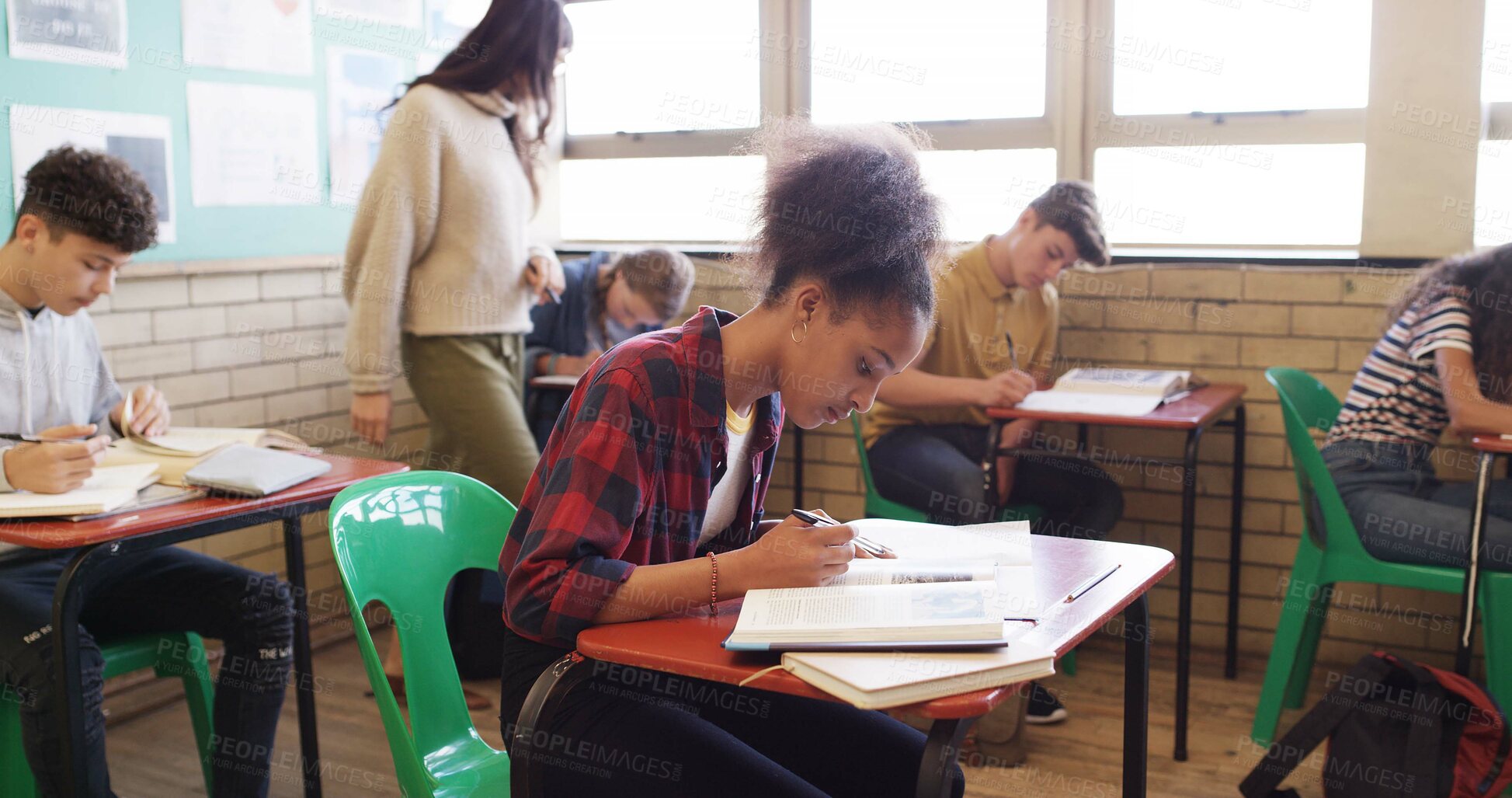Buy stock photo Writing, test and teacher walking in classroom for assessment, exam and quiz supervision. High school, academy and woman with students with assignment for education, learning and lesson progress