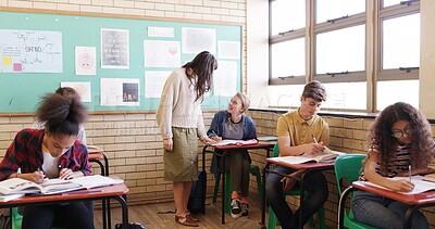 Buy stock photo High school, classroom and teacher with girl for help with test, assignment and exam question. Academy, lesson and woman with students writing assessment for education, learning and development