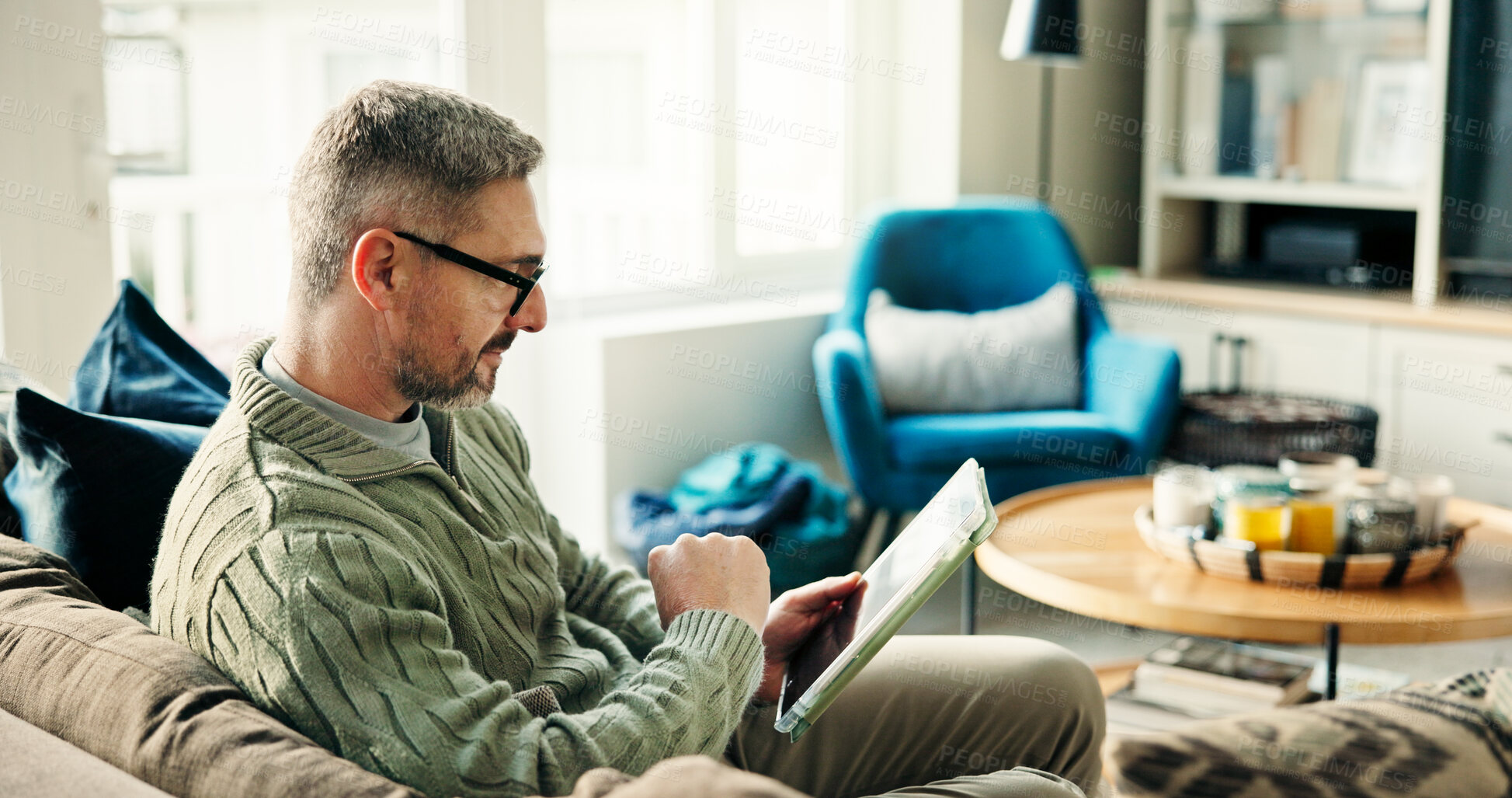 Buy stock photo Tablet, freelancer and mature man on sofa for reading news, article or report online. Technology, remote work and journalist in home to check email for headline, story and research on internet