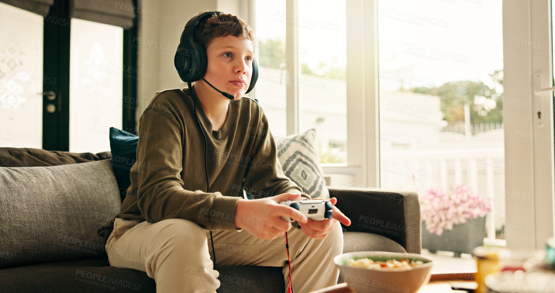 Buy stock photo Snack, video game and boy with controller, kid and subscription with challenge. Home, headset or child on sofa, online contest or audio with esports, gamer or relax with hobby, click or entertainment