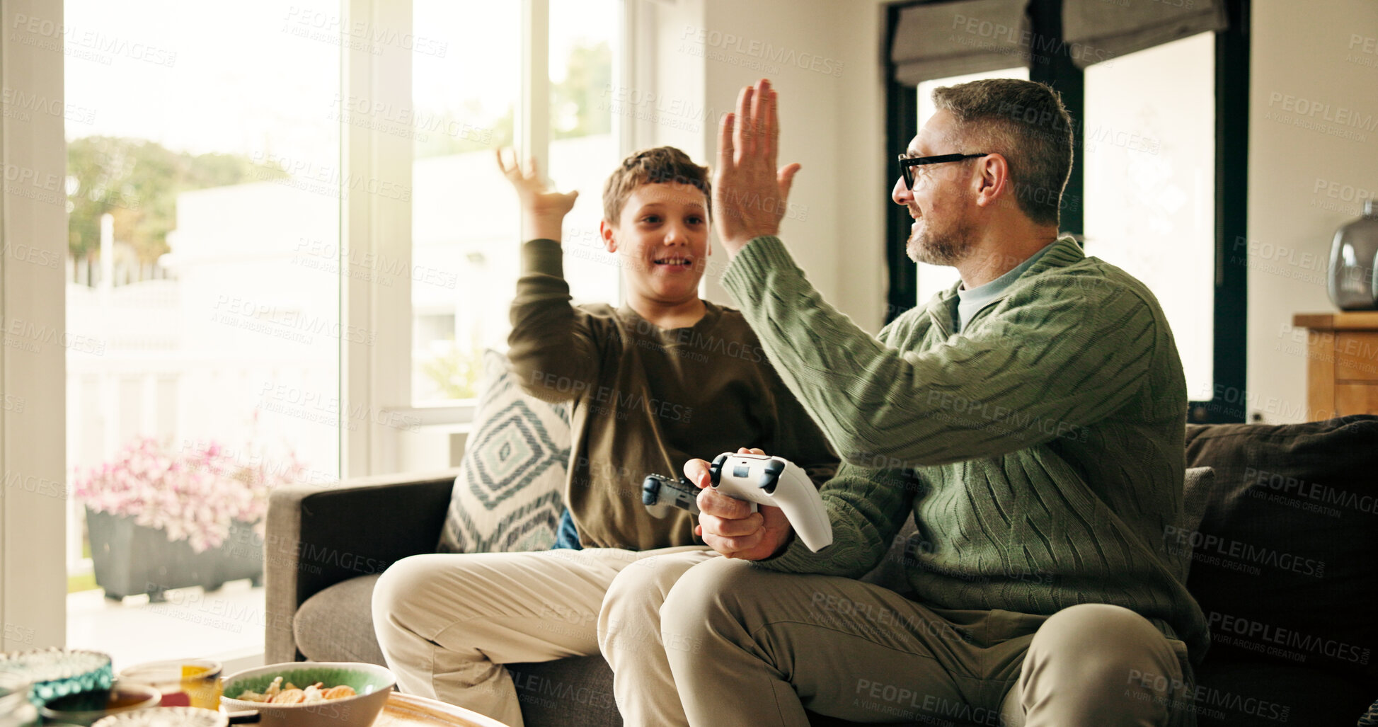 Buy stock photo Father, child and high five for video game in home, win competition or parent bonding with son. Console, happy kid and dad with hands together for success, teamwork and family celebration in lounge
