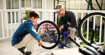 Father, child and fixing bicycle for learning, help and laugh with son at family home. Dad, kid and bike maintenance together for wheel repair, teaching and cycling hobby at patio with happy parent