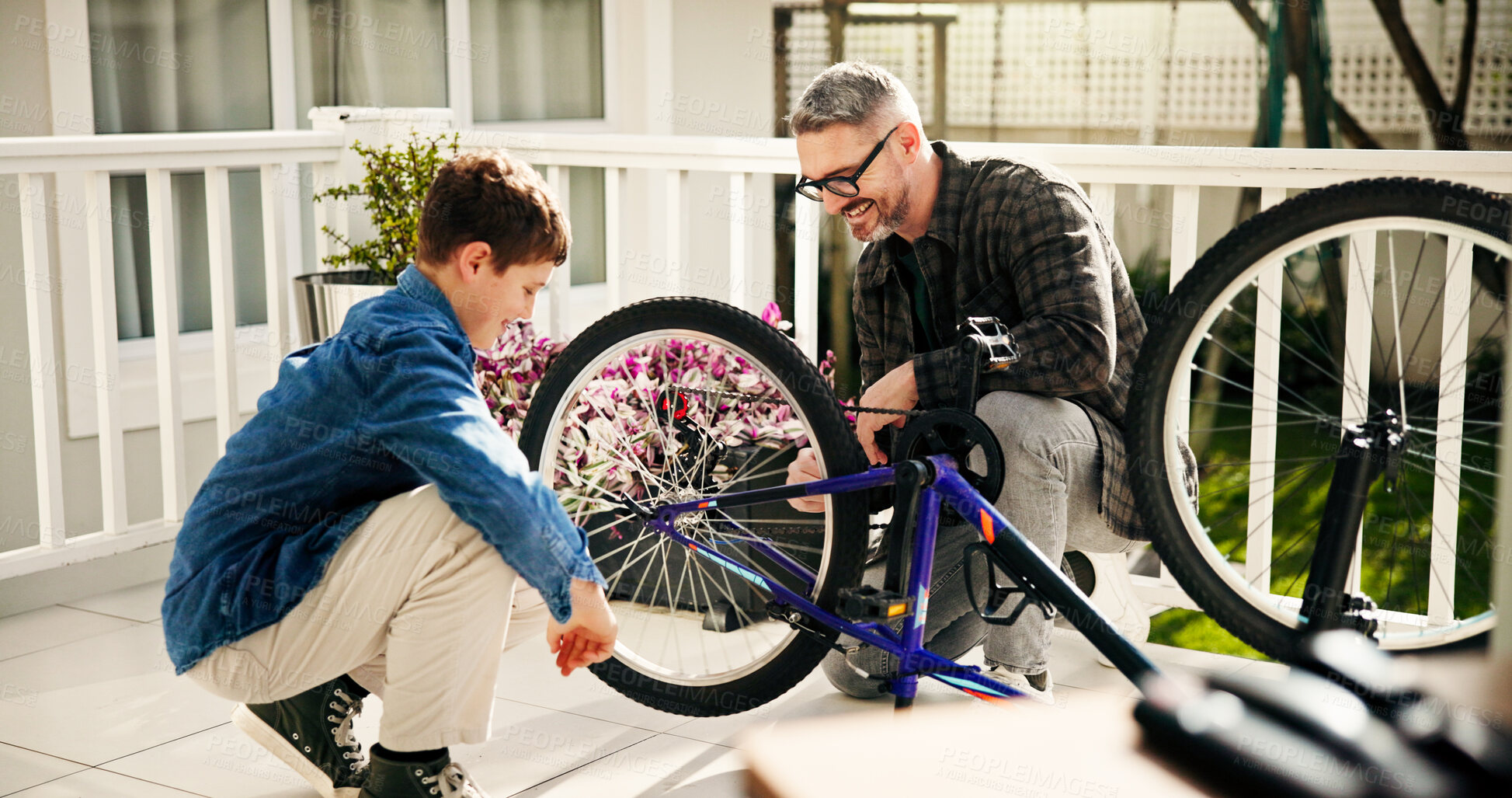 Buy stock photo Father, child and fixing bicycle for learning, help and laugh with son at family home. Dad, kid and bike maintenance together for wheel repair, teaching and cycling hobby at patio with happy parent